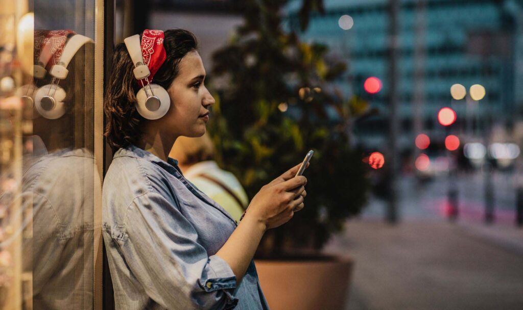 Frau hört True Crime vom Smartphone mit Kopfhörern